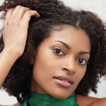 Cute young African American female with 4A curls admiring her hair health and reduced breakage from a healthy diet.