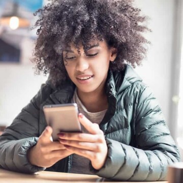 A cute black girl with healthy hair follicles researching hair shaft damage after using a flat iron to get straight hair.