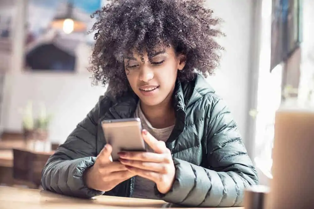 A cute black girl with healthy hair follicles researching hair shaft damage after using a flat iron to get straight hair.