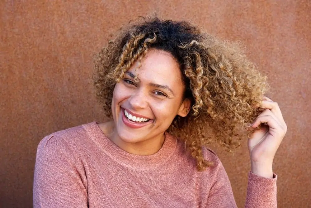 A black lady showing off the beauty of her natural curls and hair benefits of avocado oil.