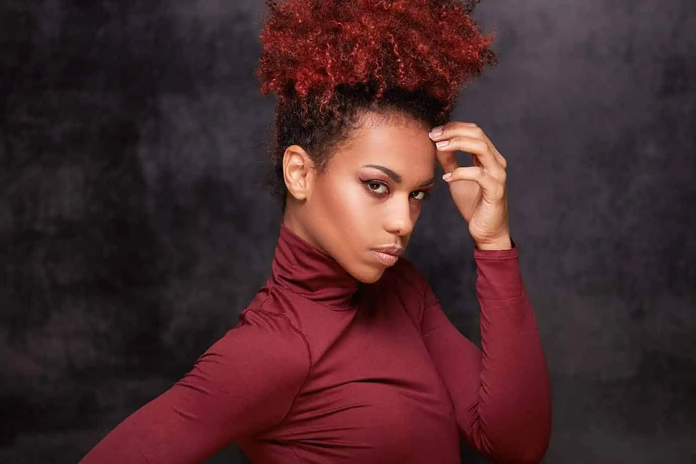 Cute African American female with dark hair after dyeing her curls a lighter hair color with a box dye.