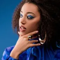 Beautiful African American wearing blue shirt, gold ear rings, and make-up after using rosemary oil for hair growth