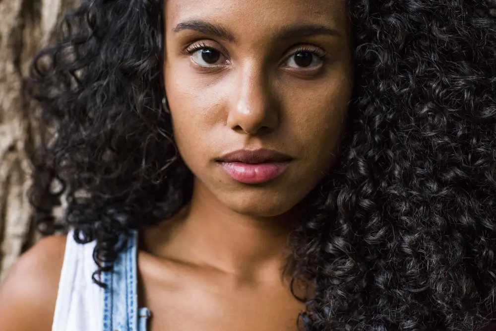 Beautiful young woman very curly type 3a hair that's been treated with clary sage oil at sunset.