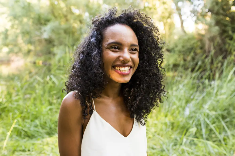 Young mixed raced female standing in a grassy field under the sunset.