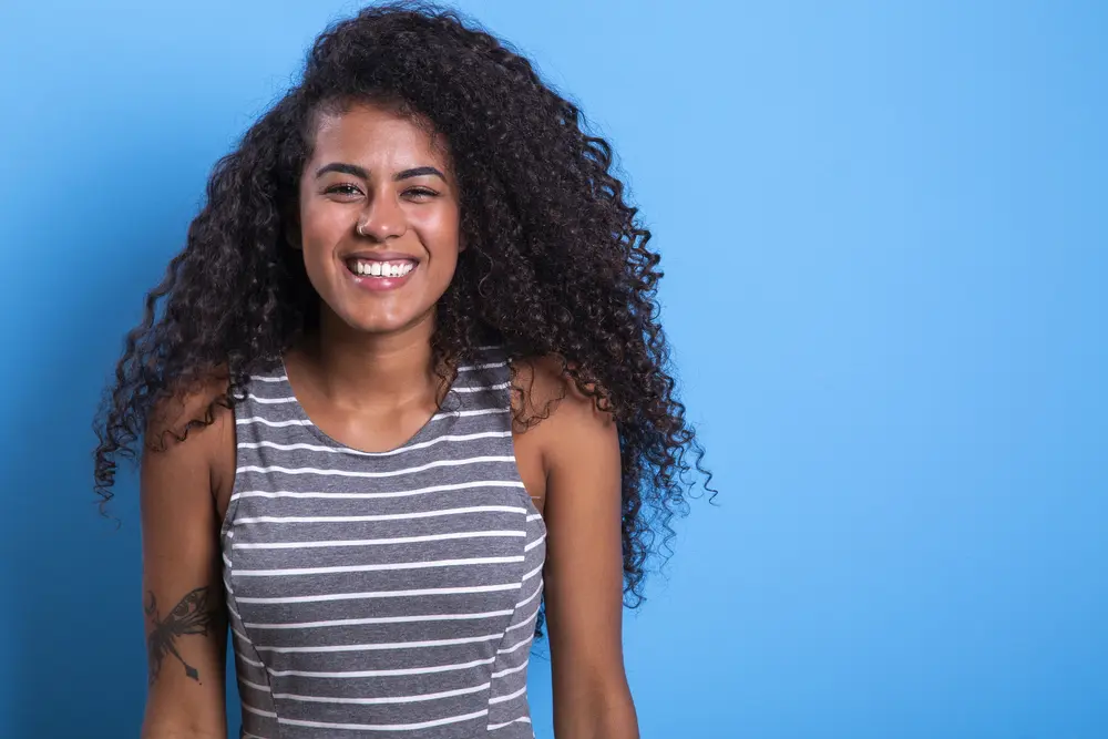 A smiling black female with long hair styled with essential oils and products with natural ingredients.