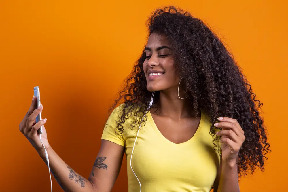 African woman taking selfie showing off her new hair growth styled with an overnight treatment with sunflower oil.