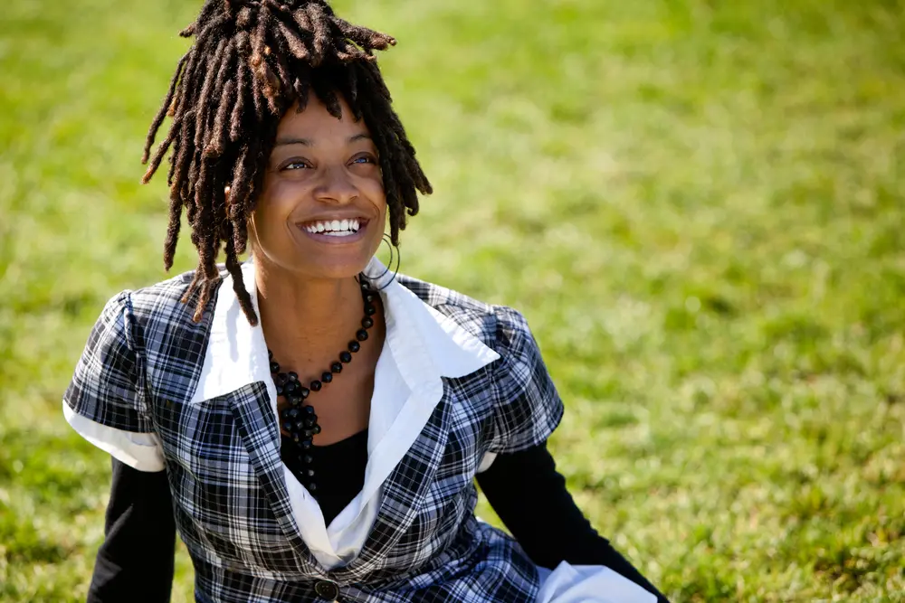 Attractive black black with a pretty smile looking upward into the distance with curly 4c hair.