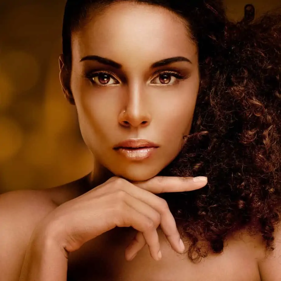 Portrait of a beautiful young African woman gently touching her face with a natural hairstyle.