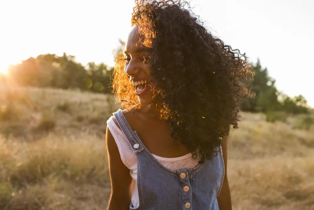 Women with clary sage oil treated hair smiling with pretty white teeth standing in the sun. 