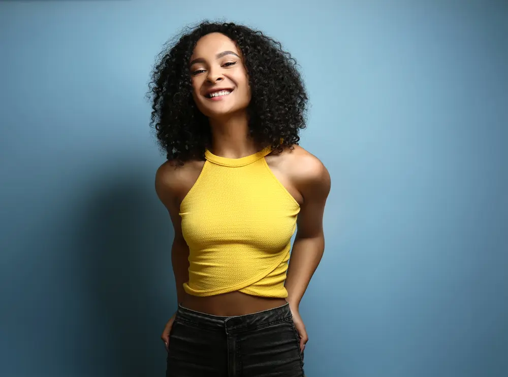 Beautiful African-American woman with oily skin and curly hair styled with hair oils with moisturizing properties.