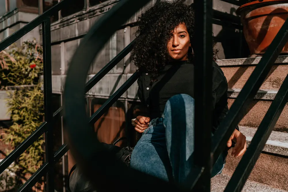 Young African Woman with type 3a hair sitting on concrete stairs in the city. 