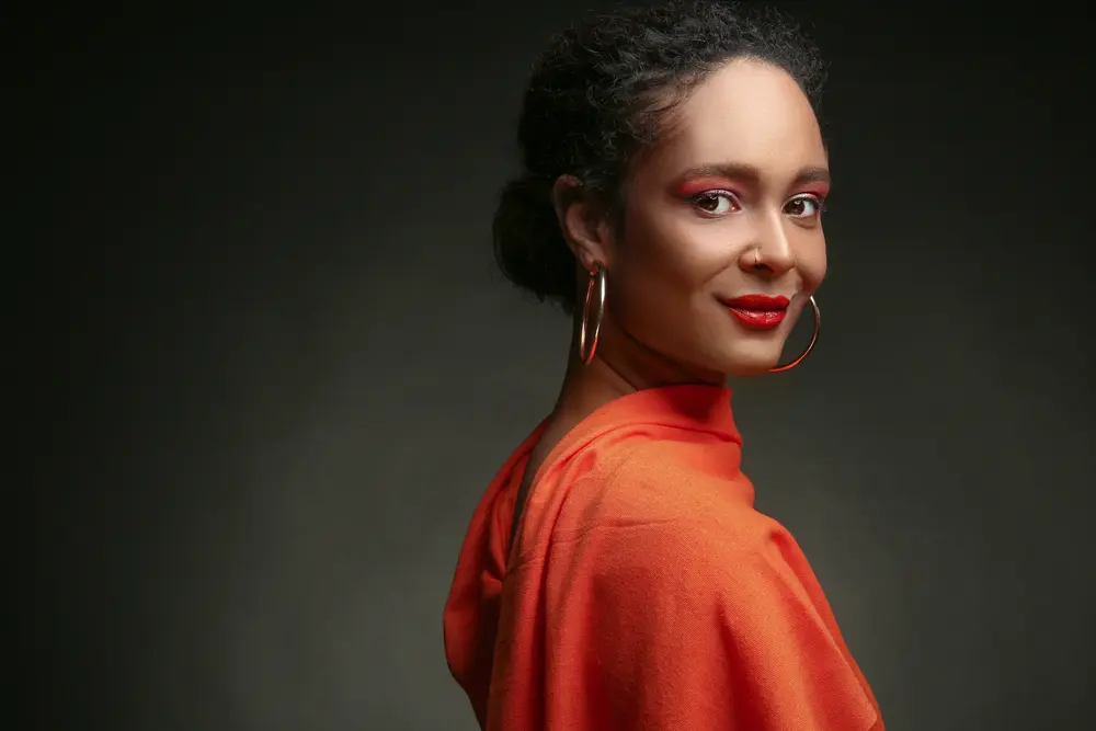 A beautiful African-American woman wearing a curly ponytail moisturized with a few drops of baobab oil.