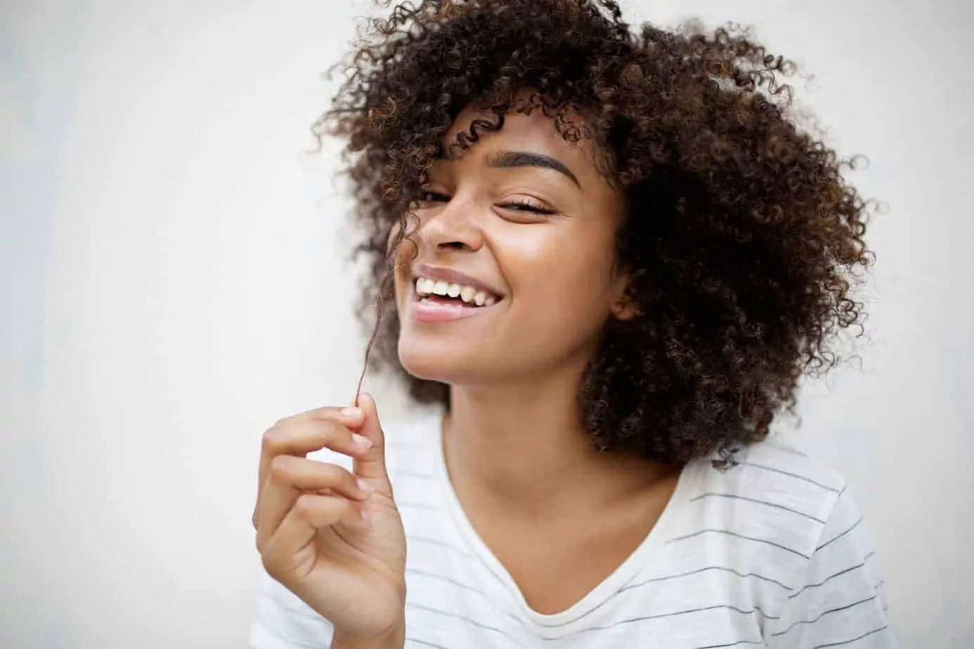 Pretty black girl checking the length of her hair by pulling one of her strands.