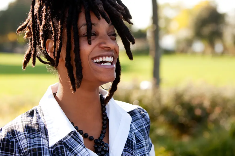 Young woman laughing after installing loc extensions in her 4c naturally curly hair.