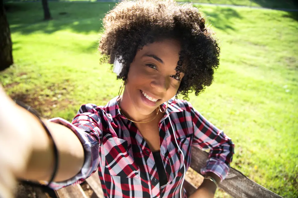 A cute young African American female with natural curls styled with olive oil and rosemary essential oil.