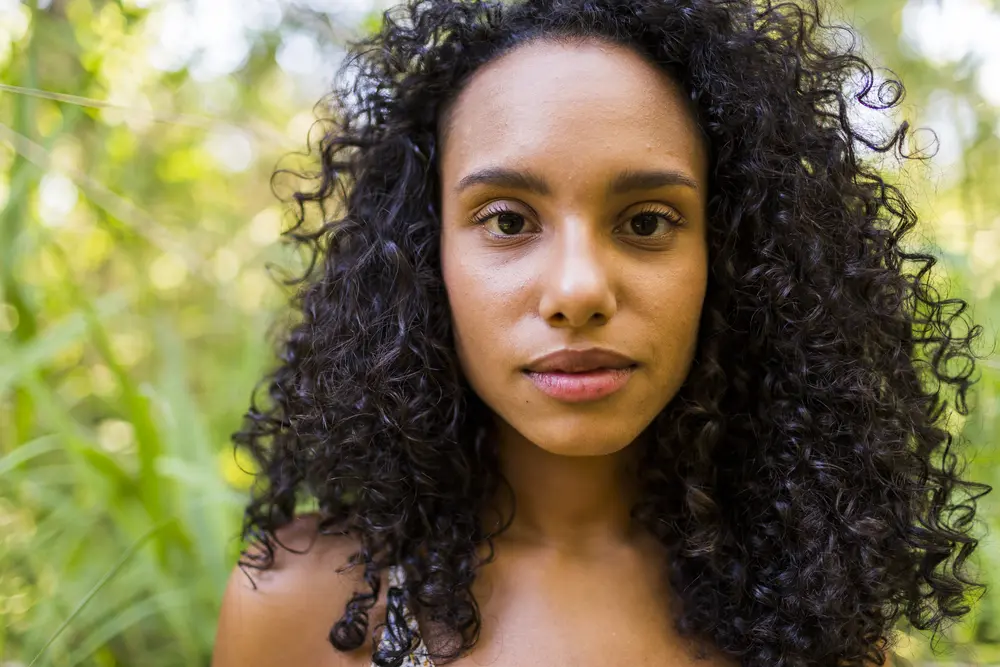 Young Afro American woman at sunset with very curly hair looking directly into the camera. 