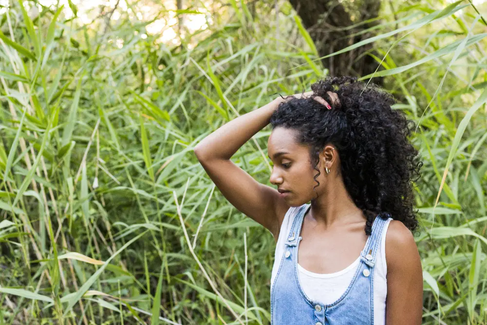 Light-skinned African American female with curls styled with rosemary hair oil and avocado carrier oil.