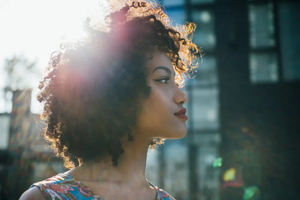 Young lady with kinky curls styled with cedarwood oils to promote hair growth and encourage blood flow.