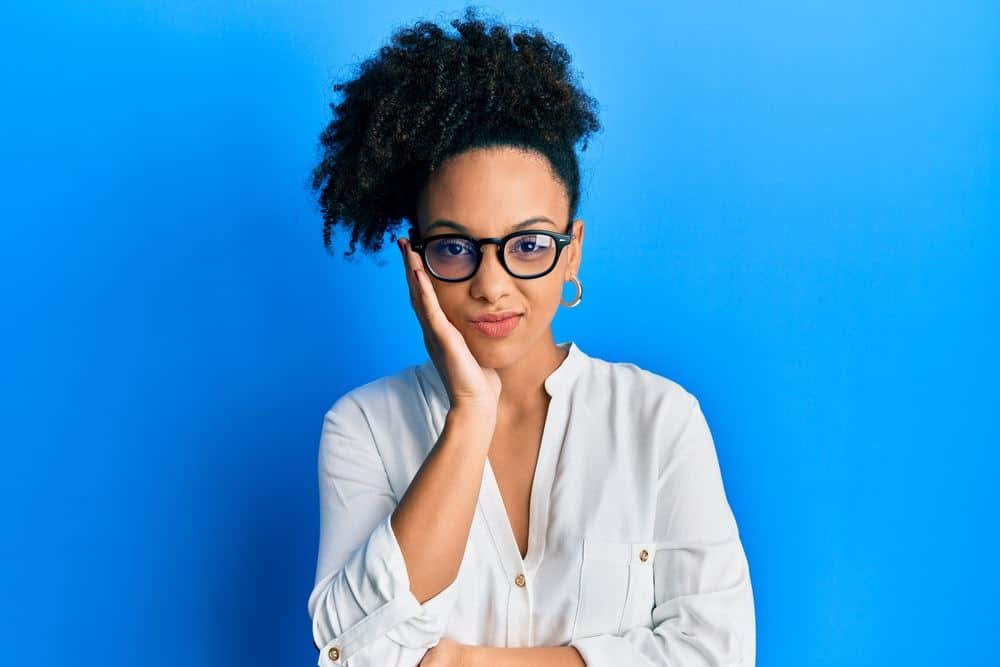 Young African American girl with hair treated with peppermint oil wearing casual clothes and glasses thinking looking tired and bored with depression problems with crossed arms.