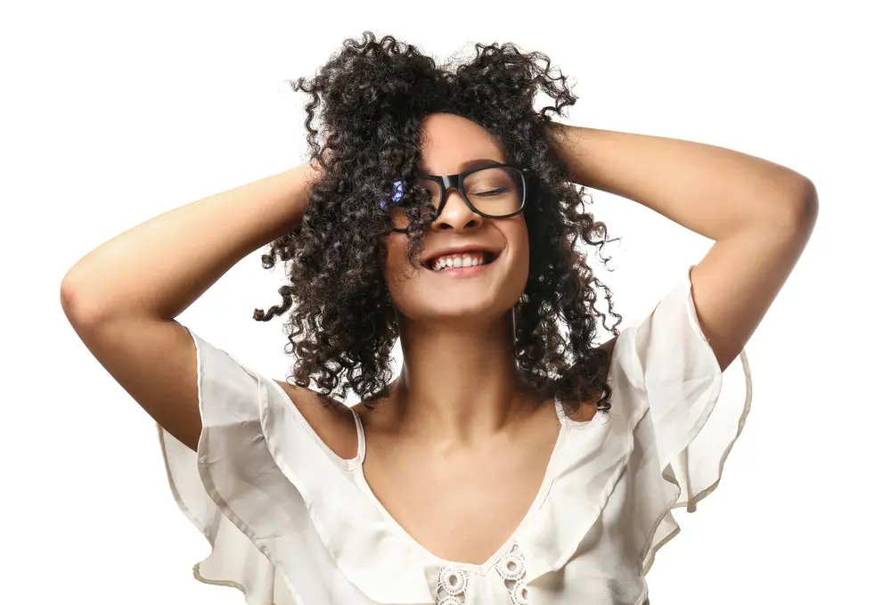 Mixed-raced girl with brittle hair and sensitive skin after using baobab seed oil to style her curly hair strands.