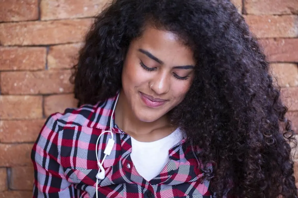 Light-skinned female with dark brown curls styled with vitamin E hair oil to maintain a healthy hair thickness.