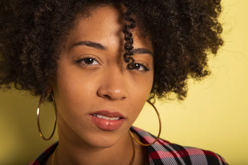 Is ylang ylang oil good for hair growth? Young African American woman isolated on yellow wall studio teen style shouting close-up.