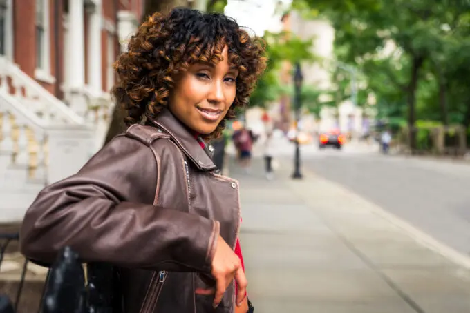 Close-up outdoor image of a black girl wearing a leather jacket with natural hair