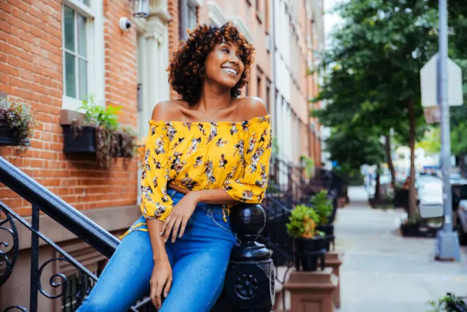 Lady leaning on a staircase railing looking into the distance with a huge smile