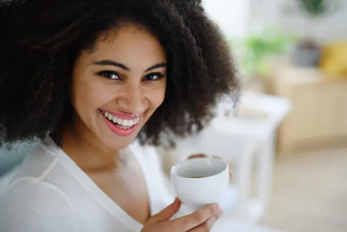 Cute girl wearing a white shirt while drinking coffee during breakfast