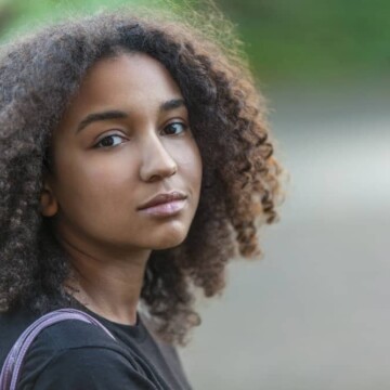 Outdoor portrait of beautiful mixed race African American female with hair that's been treated with coconut oil for hair growth and scalp care.