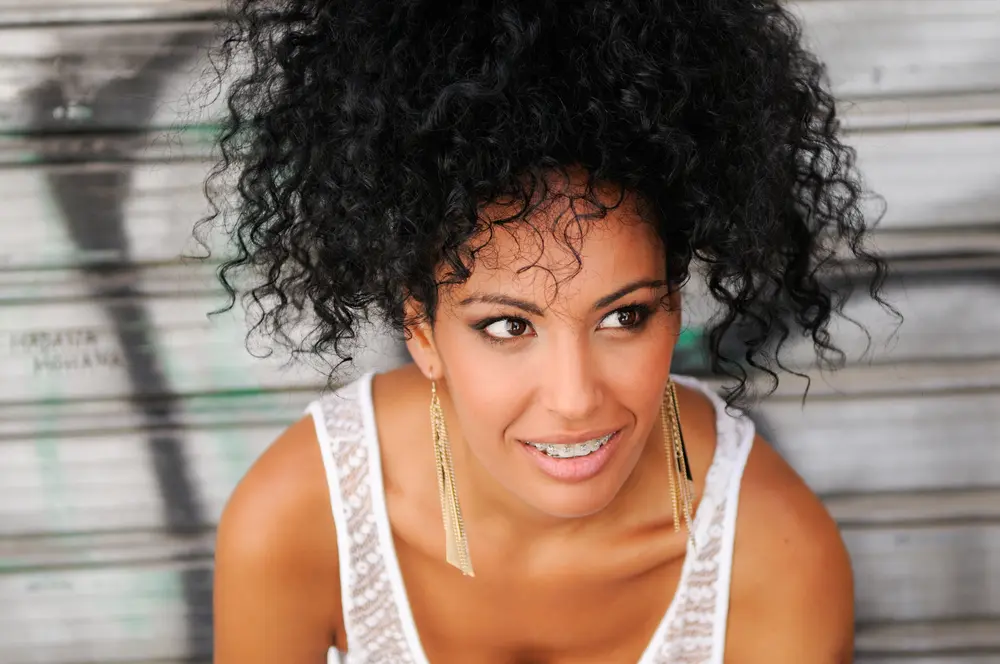 Portrait of a young black woman smiling with braces wearing tank top.