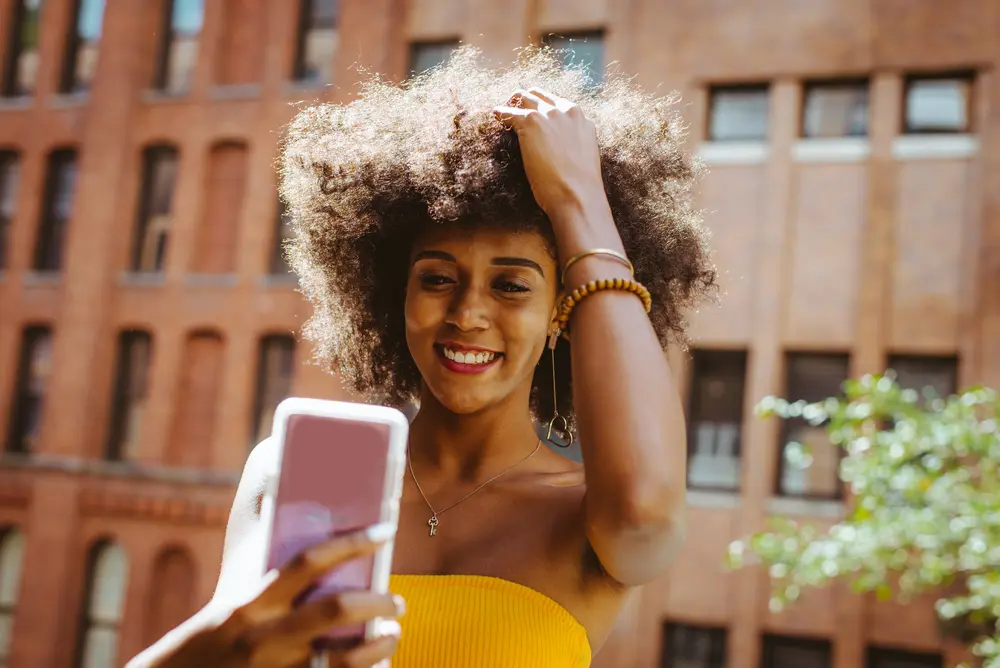 Lady with curly type 4C hair after using onion juice for several days standing outdoors. 