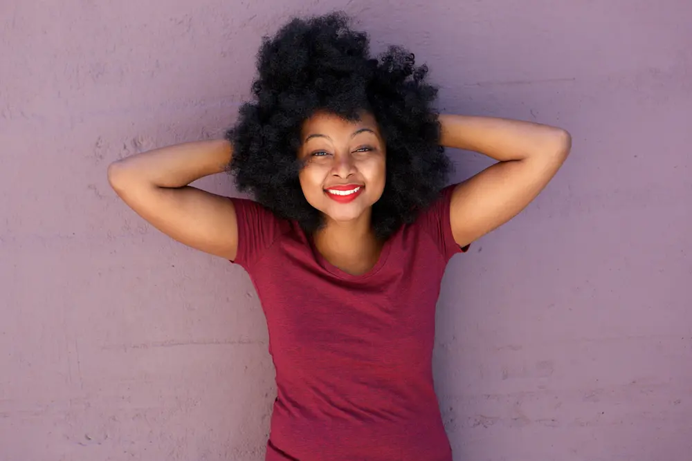 Young African American female wearing hair gel with her hands behind her head.