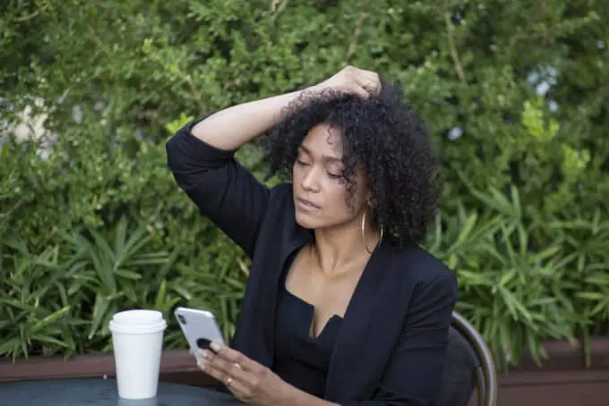 Cute black woman wearing a black dress holding her type 4A curly hair. 