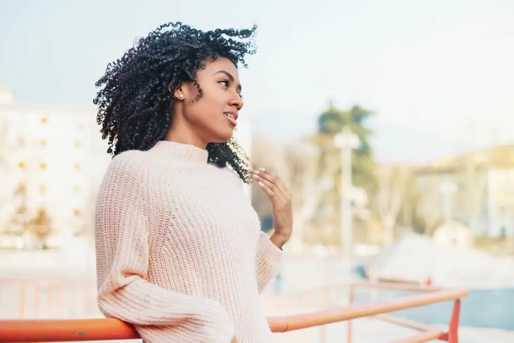 African American female with freshly washed long hair wearing a brown sweater and silver earrings. 