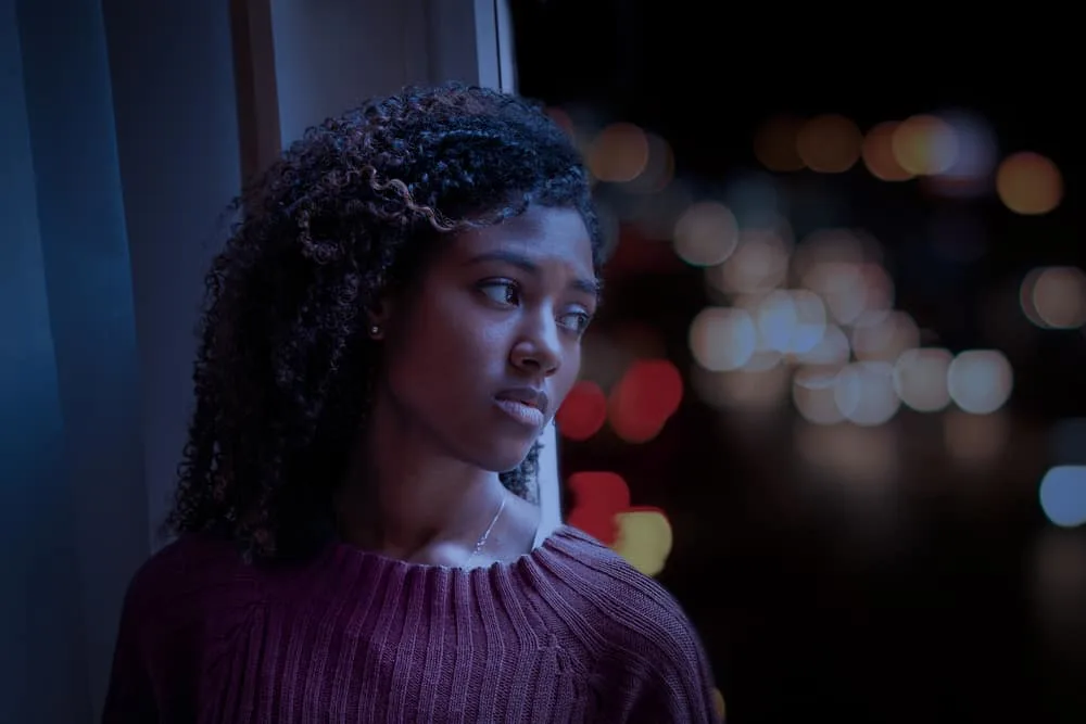 Sad female looking out of a window; looks like an advertisement or commercial for someone that's disappointed. 