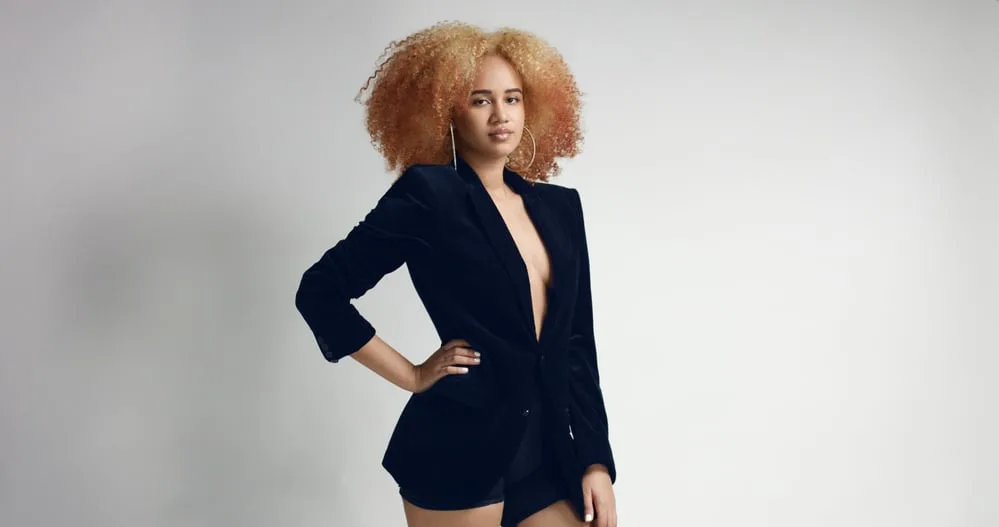 Black woman with round earrings, blonde hair, and white nail polish