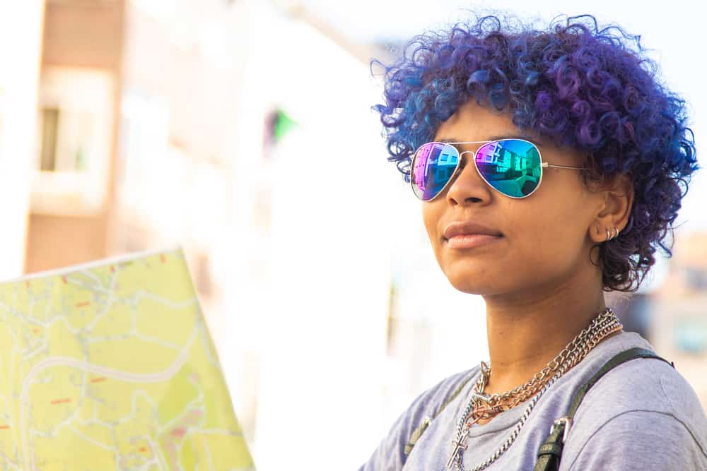  Donna che indossa sfumature arcobaleno, capelli viola-blu, orecchini e colore naturale del rossetto.