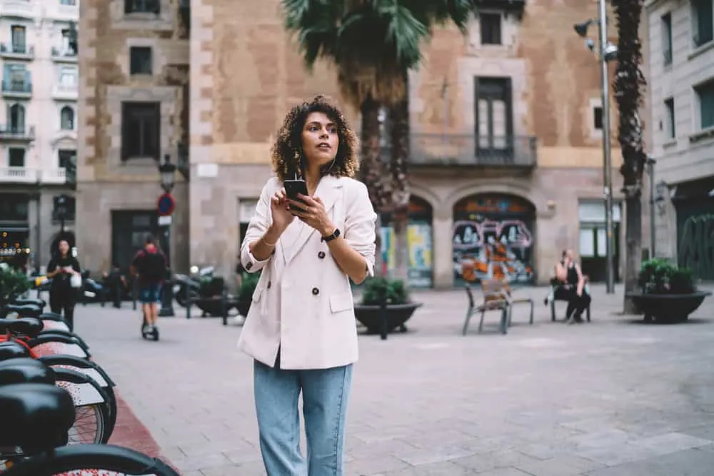 Cute adult female with natural hair wearing stone-washed jeans and a sports coat.