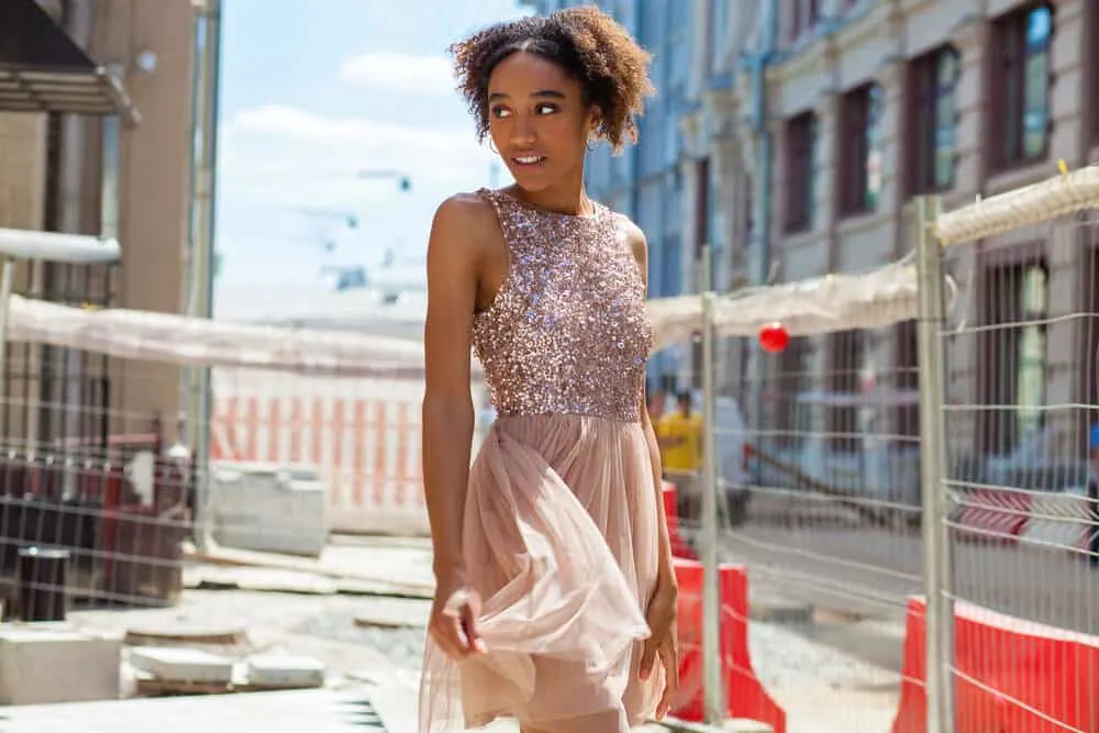 Women with type 4a curls wearing a dress while taking photos at a construction site.