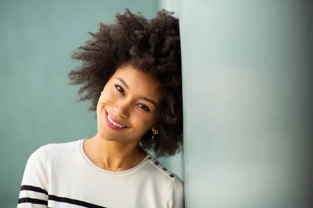 Cute African American women with an afro wearing a sweater that buttons down the shoulder. 