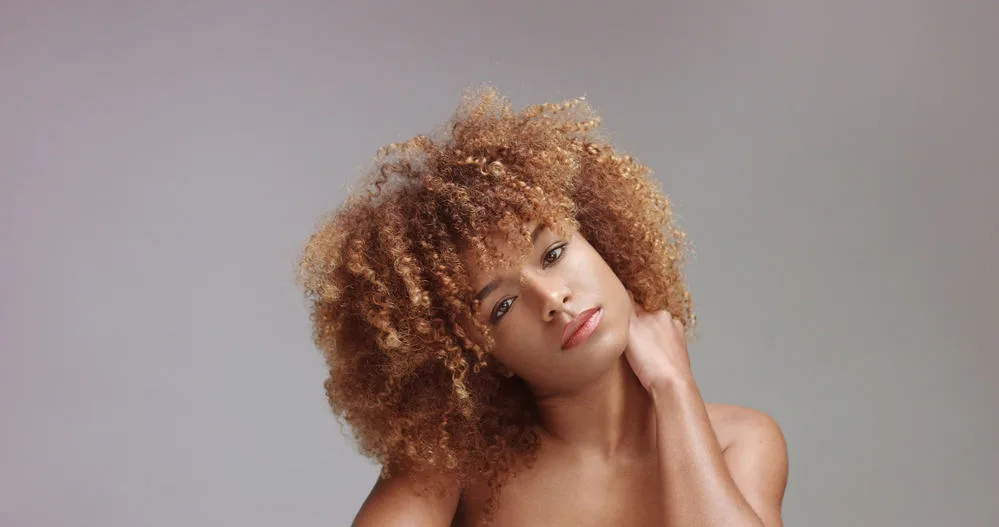 Mixed race black woman wearing red lipstick and black eyeshadow with her hand behind her neck