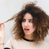 Black woman with type 3b curly hair holding her hair strand after using the squish to condish method with flax-seed gel.