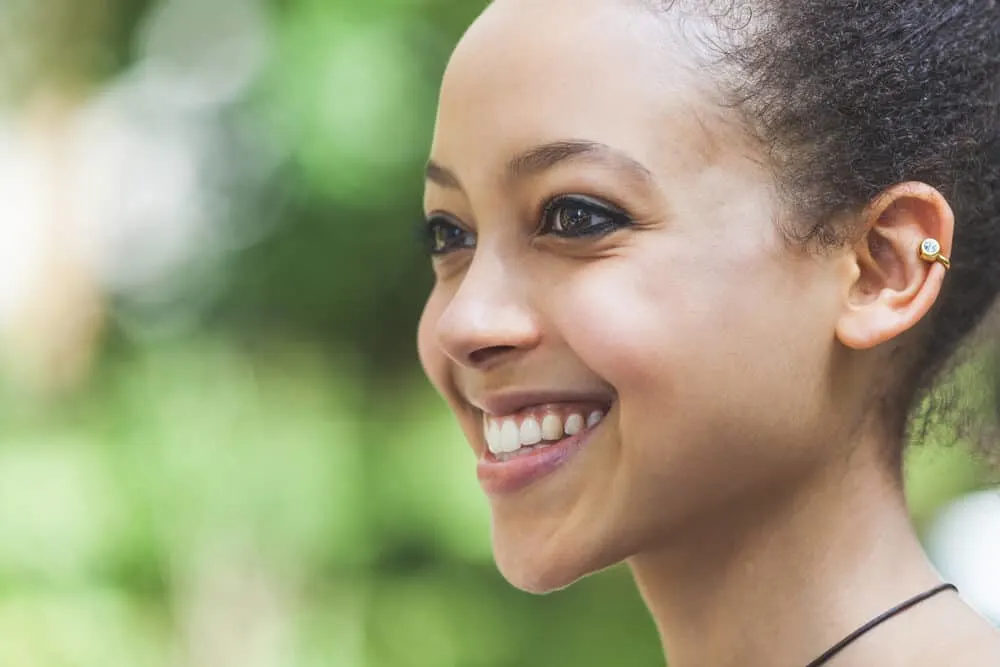 A cute black girl with lice eggs, called nits, in her hair is smiling and wondering if hair dye kills lice.