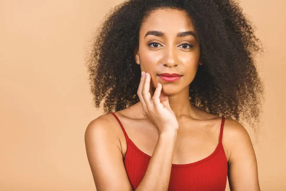 Black girl wearing a red shirt, bright red lipstick, and purple fingernail polish.