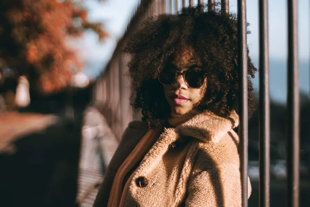 An African American female is wearing sew-in hair extensions on her wavy hair to add thickness to her existing hair.