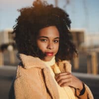 A young African American female with a type 4 hair type is showing off her own hair texture with a wash-n-go style.