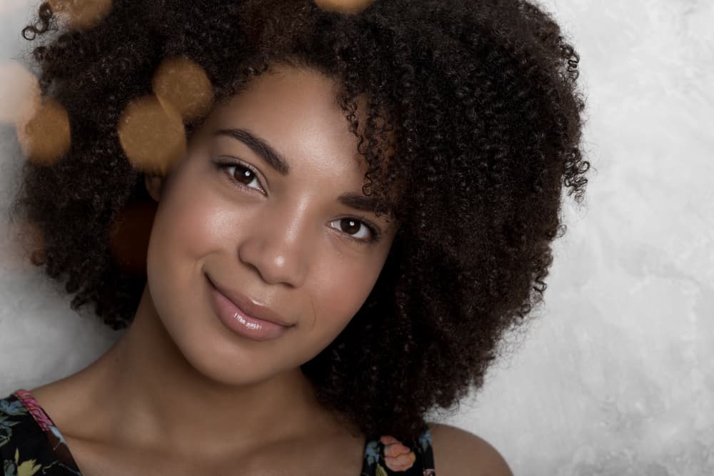  Linda mujer negra con una sonrisa genuina, con maquillaje sutil y lápiz labial rosa.