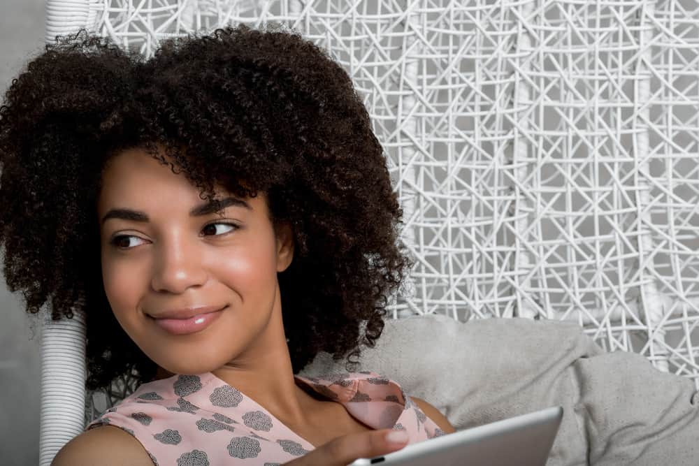  Femme portant une robe rose montrant des indices non verbaux qu'elle est à l'aise de garder un contact visuel avec un doux sourire.