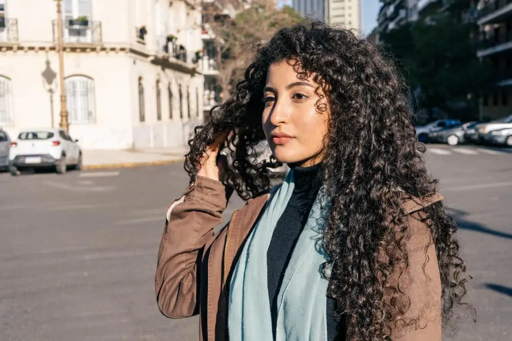 A charming Latina woman with curly hair treated with a water-soluble styling product